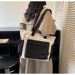 Detail of large black and white contrast tote bag featuring side drawstring pocket and strap