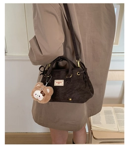 Detail of vintage brown textured handbag with bear charm and adjustable shoulder strap