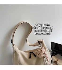 Detail of beige large capacity tote bag with adjustable shoulder strap and cute bear charm