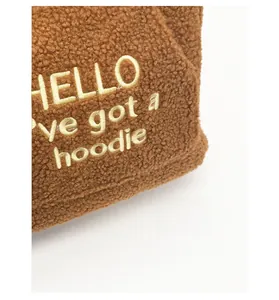 Detailed close-up of brown sherpa fleece texture with yellow embroidered text on the fabric