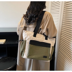 Detail of color-block nylon tote bag with utility pockets and wide webbing strap