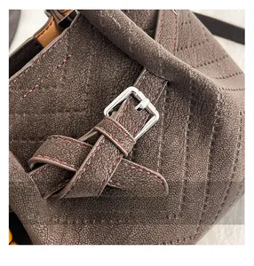 Macro shot of silver metal buckle and reinforced stitching on dark brown matte leather