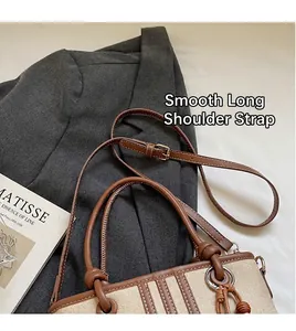 Detail of adjustable leather shoulder strap and canvas bucket bag with silver hardware