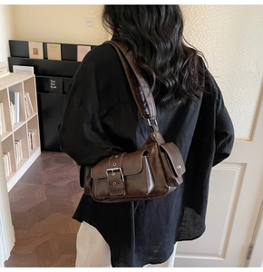 Detail of vintage brown leather crossbody bag with silver buckle worn in a library setting