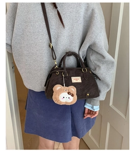 Detail of dark brown leather handbag with vintage gold hardware and plush bear charm