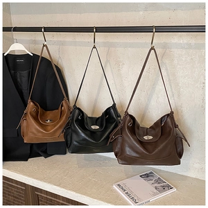 Detailed view of large leather tote bags with metal turn-lock closures in three colors