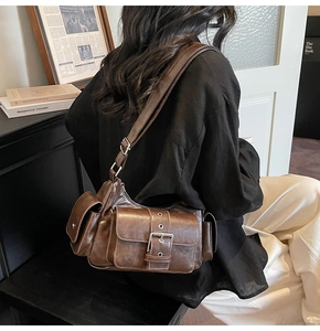 Detail of vintage dark brown leather crossbody bag featuring metal buckle and multi-pockets