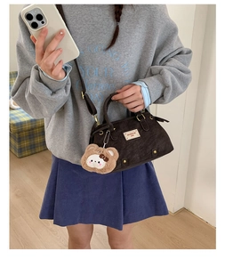 Detailed view of coffee brown corduroy shoulder bag with bear pendant and adjustable strap