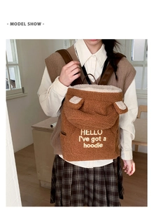 Detail of plush brown backpack with bear ears and white embroidery on lamb wool texture
