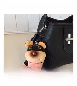 Close-up of a plush dog charm on a black lychee texture leather bucket bag with metal buckle