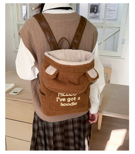 Detail of plush brown teddy fleece backpack with ear accents and embroidered text