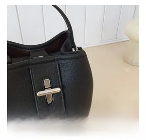 Close-up of black lychee leather bucket bag with silver metal twist-lock buckle
