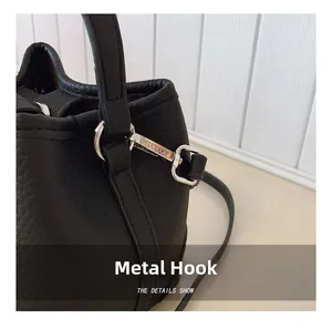 Detail shot of silver metal hook on black pebble leather bag with branding