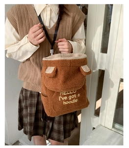 Detail of plush teddy brown backpack with bear ears and hello embroidery text