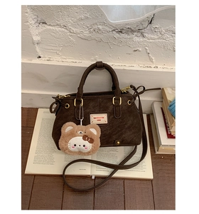 Detail of dark brown retro textured tote bag with removable strap and plush charm