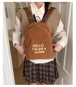 Detailed view of brown plush teddy backpack featuring gold embroidery and leather straps