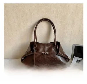 Detail of vintage brown oil wax leather tote bag with glossy texture and metal lock