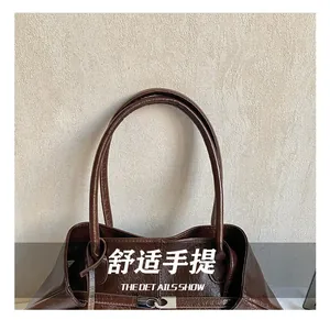 Detail of dark brown glossy leather tote with vintage texture and metal buckle closure