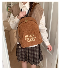 Close-up of brown plush faux shearling backpack with golden embroidered text detail