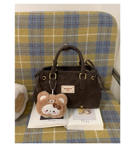 Close-up of vintage brown faux leather handbag with cute plush bear charm on handle