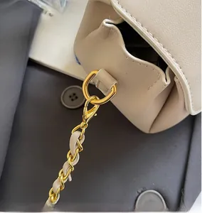 Detail of cream leather bag with gold hardware and woven chain strap on a blazer
