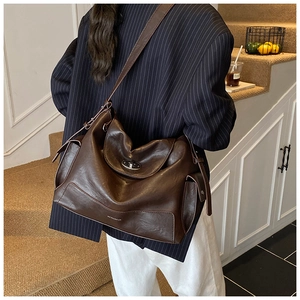 Close-up of brown faux leather tote bag showing turnover lock and side pocket detail