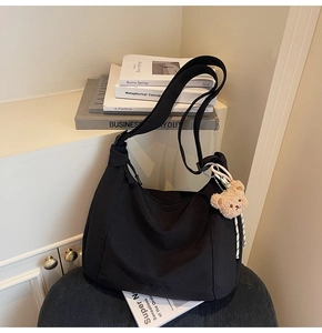 Close-up of large black hobo tote bag with a cute brown plush bear charm detail