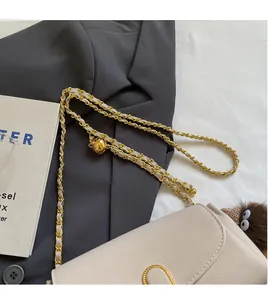 Detail of beige leather bag with gold metal ball strap adjuster and chain links