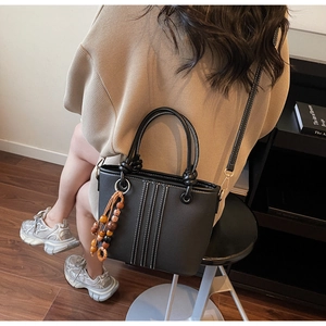 Détail du sac seau noir avec coutures blanches et breloque en perles de bois naturel