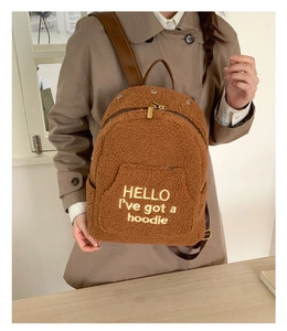 Close-up of brown faux shearling backpack with yellow embroidery and leather straps