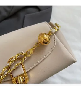 Detail of beige leather shoulder bag with golden chain strap and ball adjustment buckle
