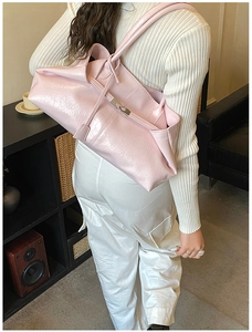 Detail of pink faux leather tote bag with glossy pleated texture and metal clasp