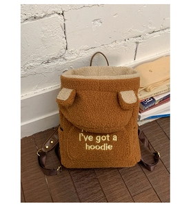 Close-up of brown plush backpack with cute ear decor and embroidered hoodie quote