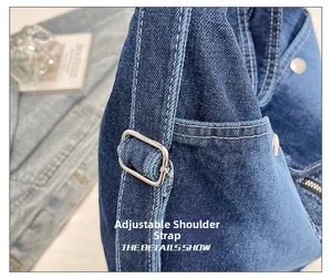 Détail de la bandoulière réglable avec boucle argentée et rivets sur sac en jean