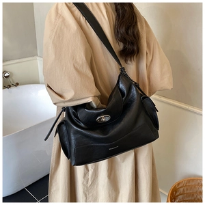 Close-up of black leather tote bag with adjustable shoulder strap and silver twist-lock closure