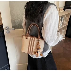 Vue détaillée du sac seau en toile beige avec finitions en cuir brun et pompon