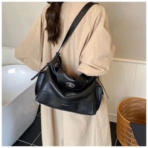 Detail of black faux leather tote with silver oval turn-lock and decorative side straps