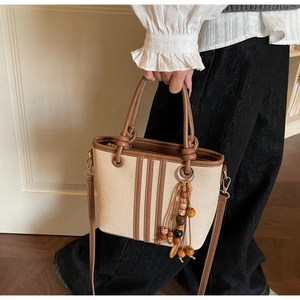 Détail du sac seau en toile avec bordure en cuir et pendentif à pompon en perles