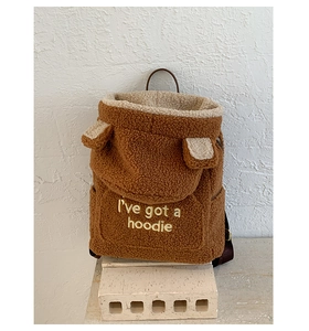 Detail of plush teddy fleece backpack with ear accents and embroidered hoodie slogan