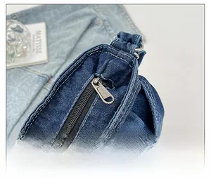 Détail de la fermeture éclair en métal argenté sur un sac en denim bleu avec surpiqûres