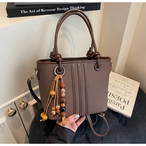 Détail du sac seau marron texturé avec perles en bois tressées et surpiqûres blanches