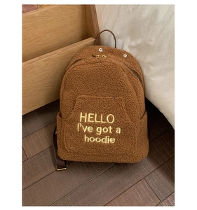 Brown teddy fleece backpack featuring gold zippers and embroidered yellow lettering detail