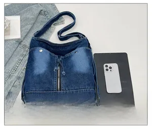 Vue à plat d'un grand sac en jean bleu avec poches à côté d'une tablette et portable