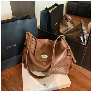 Close-up of retro brown leather hobo bag featuring a silver metal turn-lock and knot detail