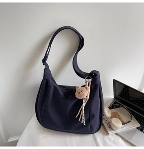 Detail of a large navy tote bag with dual zippers and a brown plush bear charm