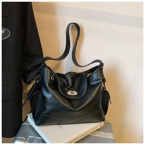 Detail of a black hobo bag with silver twist lock placed on books and a suitcase