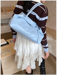 Close-up of light blue glossy leather tote bag with metallic buckle and shoulder straps