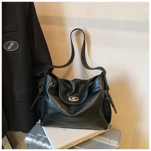 Close-up of black leather tote bag with silver oval metal twist lock and side pockets