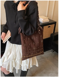 Detail of beaded suede tote bag featuring intricate floral embroidery and silk scarf handle