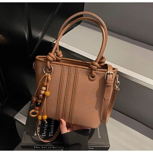 Détail d'un sac seau marron avec coutures, perles en bois et fine bandoulière réglable